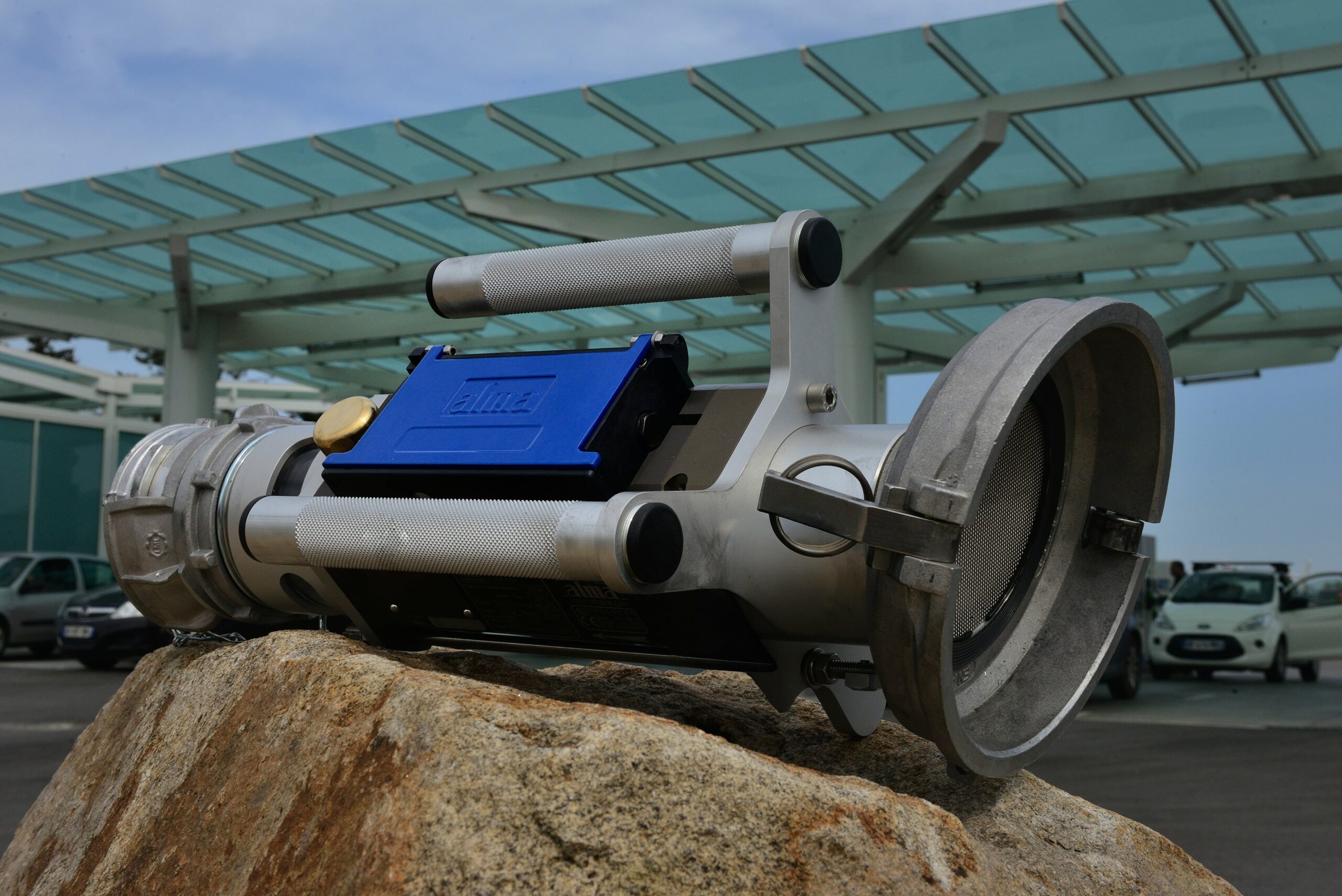 Équipement industriel de type compteur de transfert de carburant posé sur un rocher, avec son boîtier bleu et ses poignées en métal : Flexicompt.